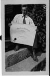 Farley Bell holding his high school diploma, ca. 1919